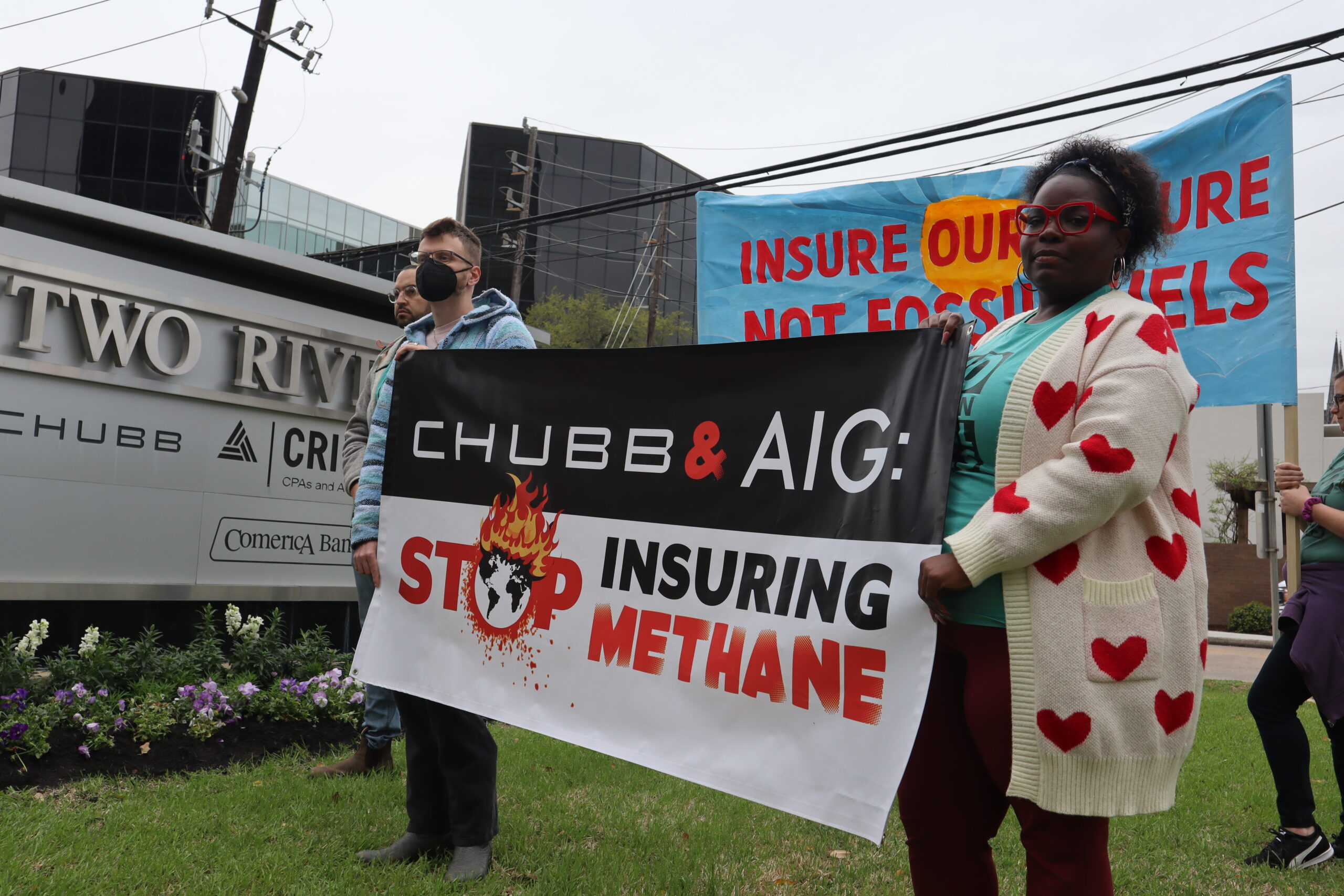 A picture of two protesters holding a banner that reads Chubb & AIG: Stop Insuring Methane